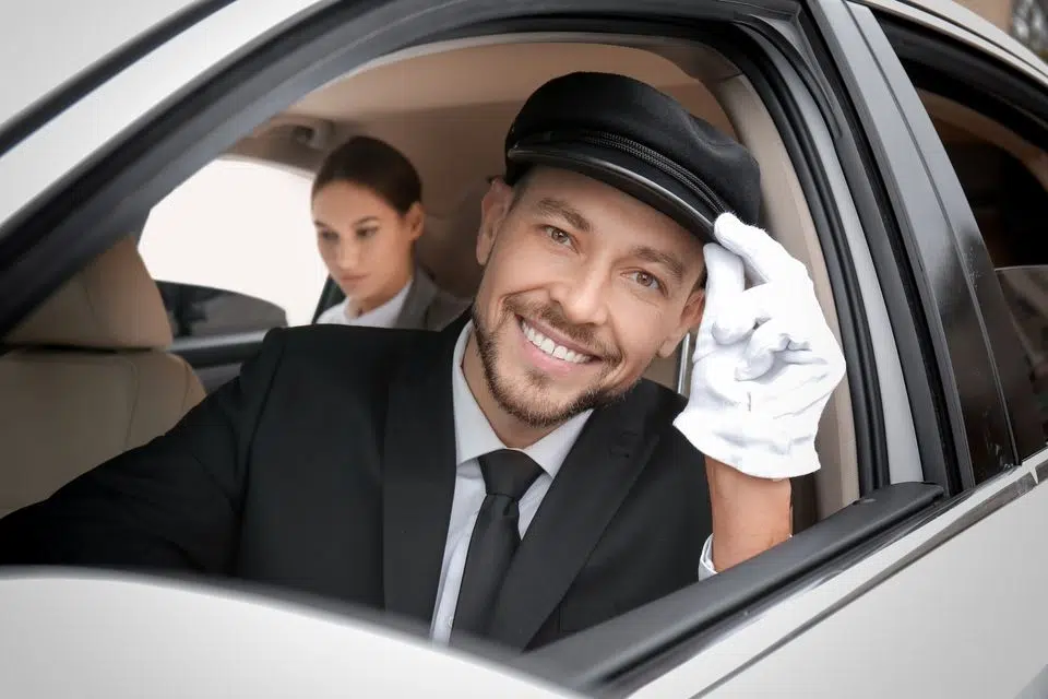 Handsome chauffeur driving luxury car